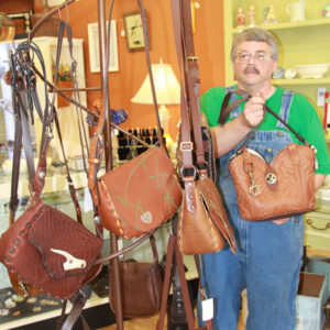 Kyle Mayes, Cobbler Cottage owner, held one of his boot purses. On the rack besides him were saddle bag purses he updated from a 1970s pattern.