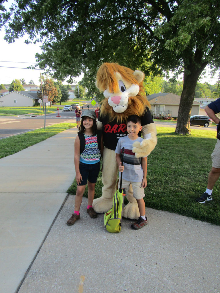 Dare Lion Darren hugged Bernadette and Vincent Badami, children of Charles and Elizabeth Badami, on the first day of school at St. Gregory’s.