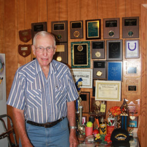 Weldon said he enjoys pitching horseshoes. Here he stands next to some of the 84 trophies and plaques, he and his wife, Eldora, have received. 