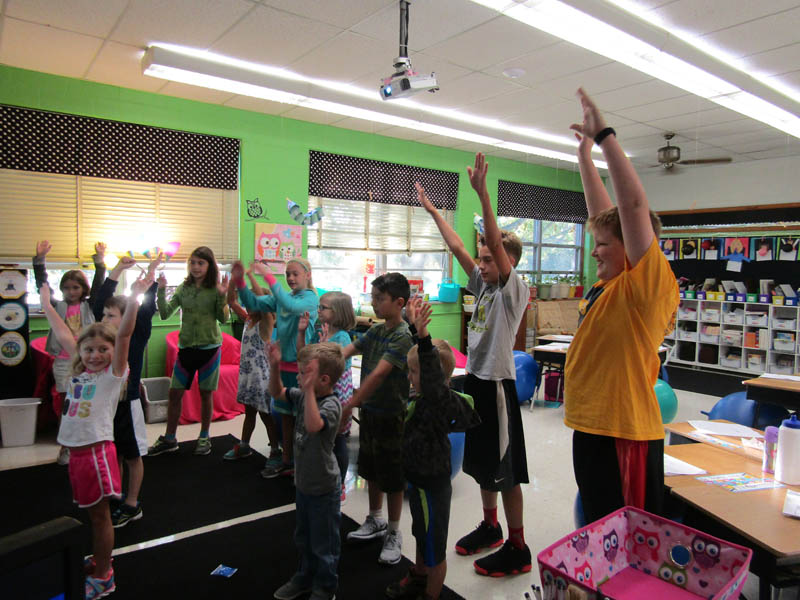 Students act out being on a roller coaster with frightened faces and screaming during a get-to-know-you activity.