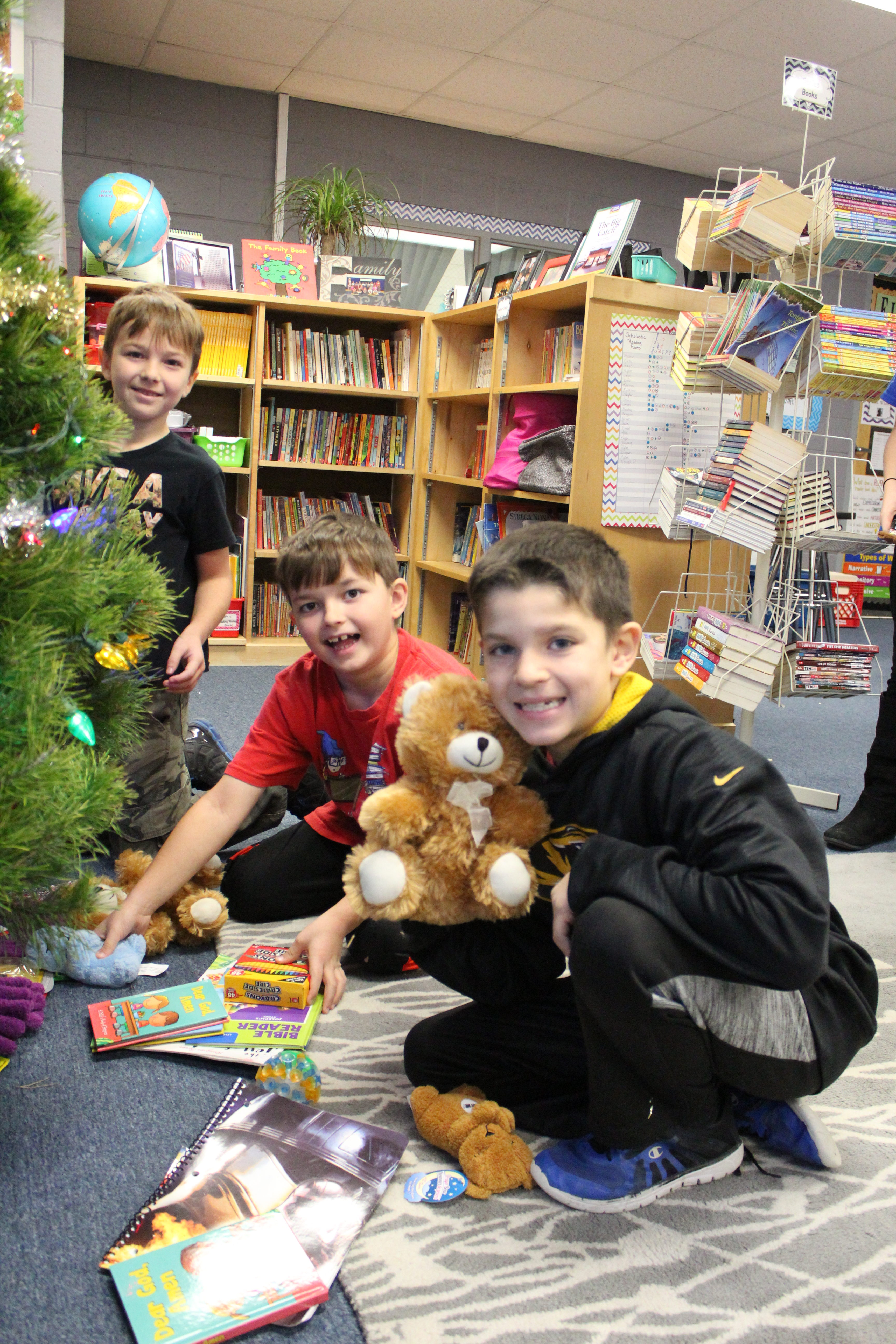 Matthew Fletcher, Austin Adwell and Drew Dack place toys they purchased to donate under the tree. 
